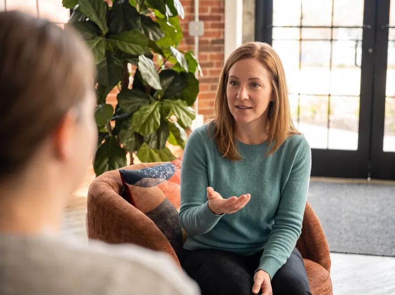 A HearthWell counselor and client in a one-on-one therapy conversation in a warm brick-walled room