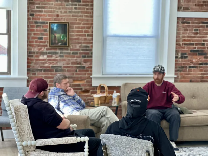 A HearthWell group in session together in a warm brick room, connecting and supporting one another